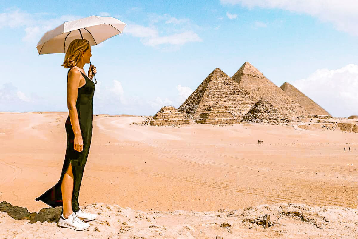 A-wonderful-view-of-a-foreign-tourist-wearing-a-black-dress-in-front-of-the-pyramids-and-holding-an-umbrella-in-her-hand